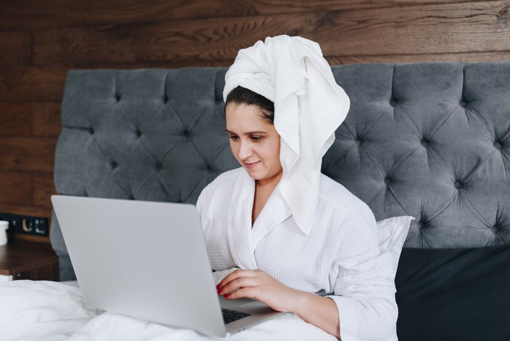 The future of work is self-management: a woman sitting in bed, working on her laptop.